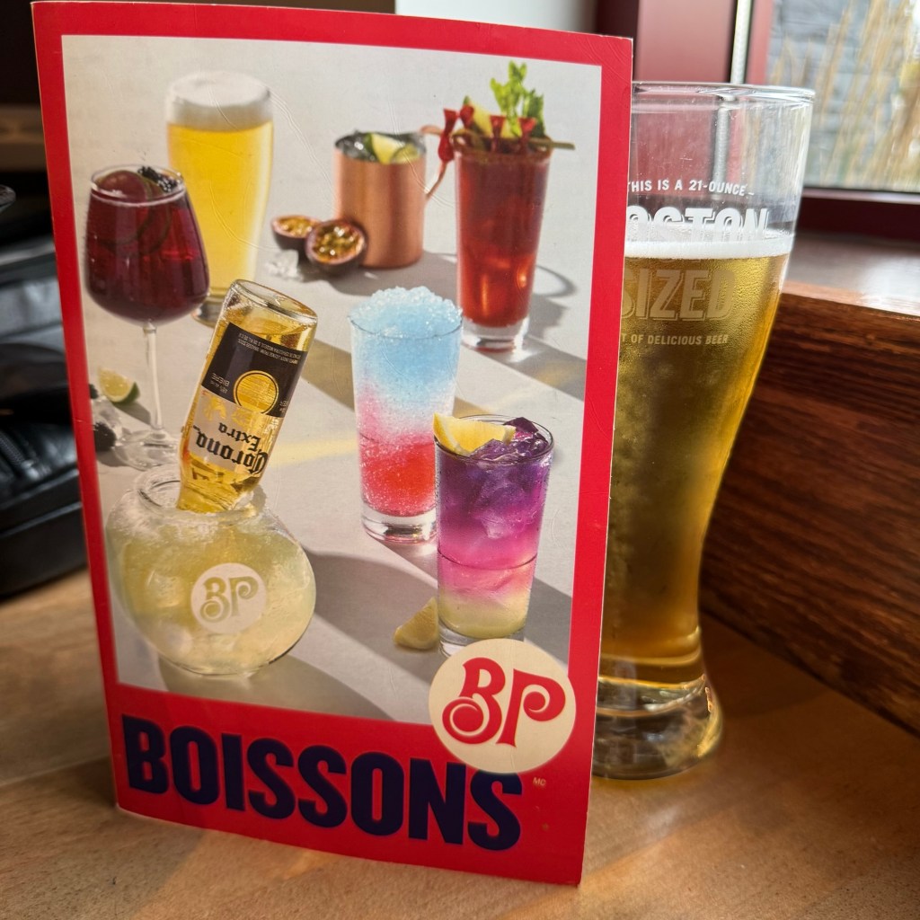 A drinks menu featuring a variety of colourful cocktails and beverages including beer, displayed alongside a tall glass of golden beer.