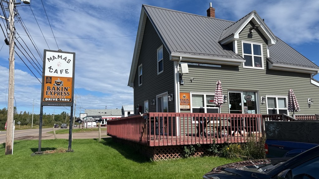 A cafe named 'Mama's Cafe' with a sign for 'Bakin' Express' drive-thru, located in a house-like building with a deck and striped umbrellas.